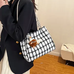 Classic black and white checkered tote bag with chain strap and plush ball charm on model