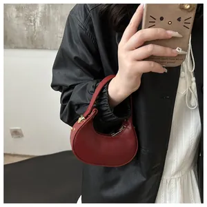 Gros plan du sac croissant rouge en cuir brillant avec détails de fermeture éclair dorée