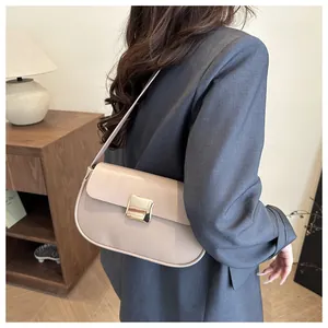 Sac à bandoulière beige élégant avec boucle dorée porté par un mannequin avec style