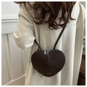 Detail of heart-shaped crossbody bag with woven texture and dual zipper closure