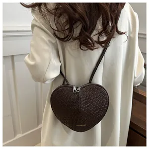 Detail of dark brown heart-shaped woven bag showing intricate texture and dual zippers