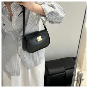 Détail d'un sac besace noir minimaliste avec boucle dorée et fine bandoulière