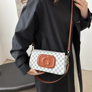 Retro shoulder bag with geometric monogram print and brown leather strap on model