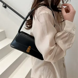Elegant black minimalist shoulder bag with vintage gold buckle on white stairs