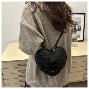 Chic black heart-shaped woven crossbody bag shown on model for a stylish casual look
