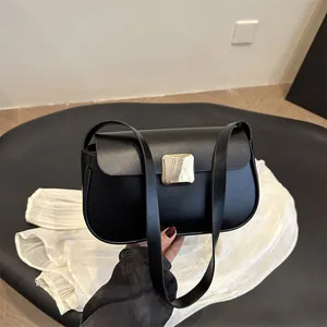 Sac à bandoulière noir mat minimaliste avec boucle dorée porté à la main