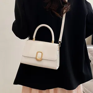 Minimalist white leather square handbag with golden buckle worn by a model in a black suit