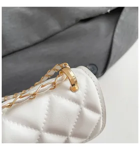Macro detail of white quilted crossbody bag with gold chain strap and D-ring hardware