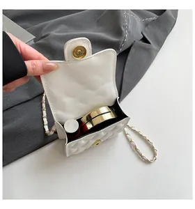 Detail view of white quilted mini bag interior with lipstick and compact makeup case