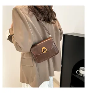 Detail view of brown vintage saddle bag with gold U-shaped metal buckle on a model