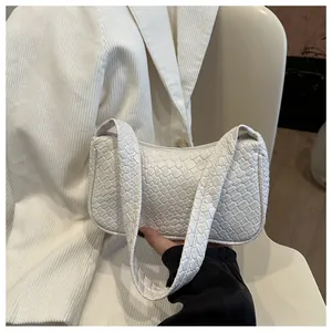 Detail of creamy white woven texture and crescent shape on minimalist shoulder bag