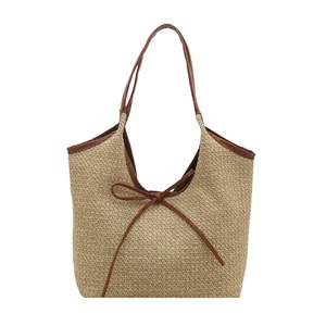 Straw woven tote bag with brown leather trim and a front bow knot for a vacation style