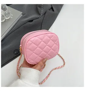 Détail du sac matelassé rose avec chaîne dorée sur fond de blazer gris chic