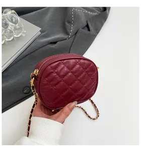 Détail du petit sac rond matelassé bordeaux avec chaîne dorée et texture cuir élégante