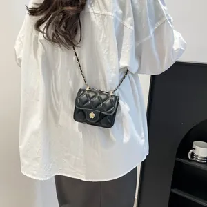 Mini black quilted crossbody bag with flower buckle and gold chain strap shown on model