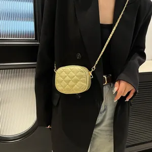 Mini sac rond matelassé doré champagne avec bandoulière chaîne porté par un mannequin