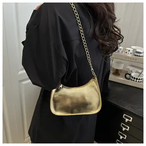 Detail of golden crescent shoulder bag with pleated texture and thick chain strap