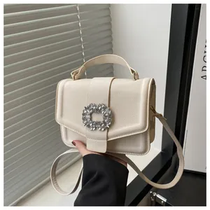 Detail of elegant cream faux leather handbag featuring a luxury rhinestone square buckle