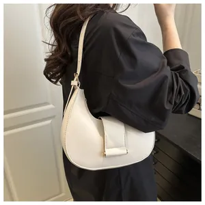 Close-up of white minimalist crescent bag featuring a buckle strap and soft leather finish