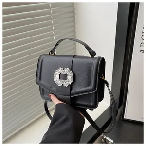 Detail of black lychee grain leather bag with a crystal-encrusted square buckle