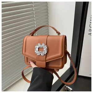 Detailed close-up of brown pebbled leather texture and crystal buckle on luxury handbag