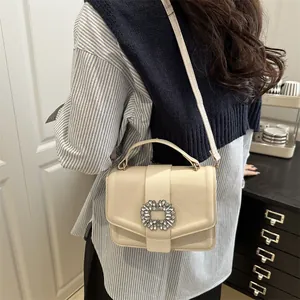 Elegant cream leather crossbody bag with sparkling crystal buckle and top handle