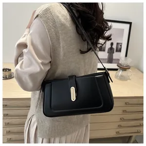 Detail of a black minimalist leather underarm bag with a golden metal buckle closure