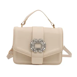 Cream textured leather handbag with sparkling rhinestone buckle and top handle strap