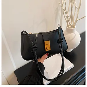 Detailed view of black retro leather handbag with gold twist lock and corded strap
