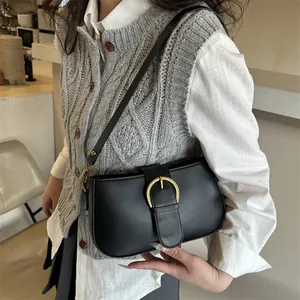 Sac à bandoulière noir élégant avec boucle fer à cheval dorée dans un décor de café