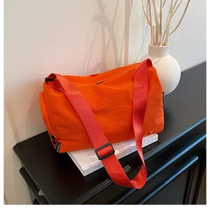 Détail d'un sac messager en nylon orange vif avec fermeture éclair et sangle griffée