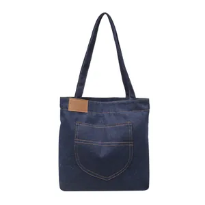 Deep blue denim tote bag with contrast stitching and brown leather accent