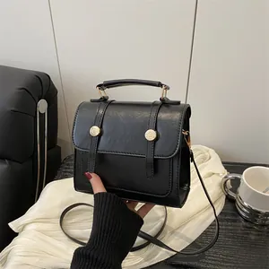 Sac à main minimaliste noir en cuir avec boucles dorées et bandoulière amovible