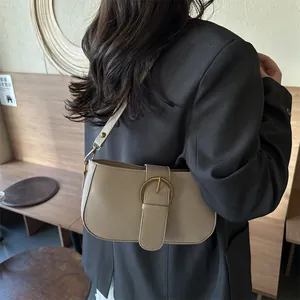 Sac sous le bras minimaliste en cuir beige avec boucle dorée ronde sur un mannequin