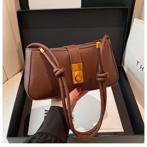 Detailed view of deep brown baguette bag with golden buckle and sleek leather texture