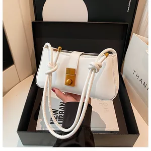 Detail of white leather shoulder bag featuring a gold buckle and knotted rope strap