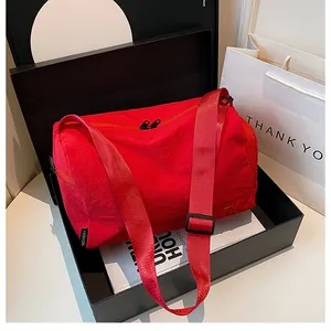 Détail du sac cylindrique en nylon rouge dans une boîte cadeau avec étiquette de mode