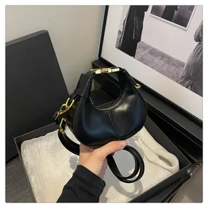 Détail d'un mini sac demi-lune en cuir noir avec ferrures dorées et bandoulière
