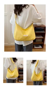 Detail van gele grote crossbody tas met fashion label en een brede schouderriem