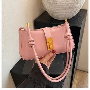 Detail of pink leather handbag with gold metal buckle and knotted shoulder strap