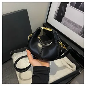 Détail d'un sac demi-lune noir montrant les ferrures dorées et le cuir synthétique