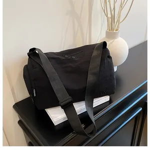 Détail du sac messager en nylon noir minimaliste avec bandoulière réglable et poche