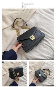 Detail of black crossbody bag with white stitching, gold hardware and chain strap