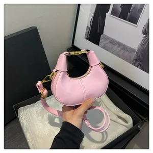 Détail du sac bandoulière rose en forme de demi-lune avec ferrures dorées et chaîne