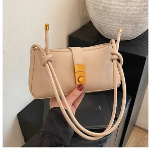 Close-up of beige PU leather underarm bag featuring a stylish knotted strap and gold lock