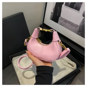 Vue détaillée du mini sac croissant rose avec fermoirs dorés et texture de cuir finie