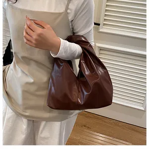 Detail einer dunkelbraunen Ledertasche mit einzigartiger Faltenstruktur und weichem Design