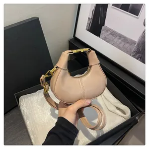 Détail d'un mini sac croissant en cuir mat avec fermoir en métal doré brillant