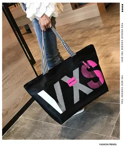 Detail of a black large-capacity tote bag with striped straps and pink VXS letter print