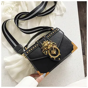Detail of black pebbled PU leather square bag with gold lion head buckle and rivets